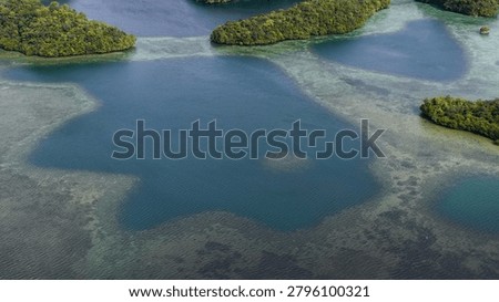 High angle shot of green limestone islands surrounded by clear turquoise waters and coral reefs.
