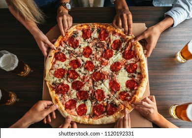 High angle shot of a group of unrecognizable people's hands each grabbing a slice of pizza - Shutterstock ID 1120192331