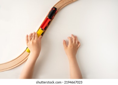 High angle shot of a kids hands playing with wooden toy train on white background with blank space for text with top view.  - Shutterstock ID 2194667023