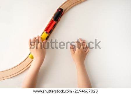 High angle shot of a kids hands playing with wooden toy train on white background with blank space for text with top view. 