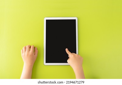 High angle shot of a little kid using a digital tablet with tablet computer on green background in vertical with copy space. - Powered by Shutterstock