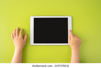 High Angle Shot Of A Little Kid Using A Digital Tablet With Tablet Computer On Green Background In Horizontal With Copy Space.