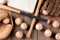 High Angle Shot Of Old And Use Baseball Equipment On A Rustic Wood Surface. Items Include, Baseballs, Bats, Home Plate, Catchers Mitt And Glove.