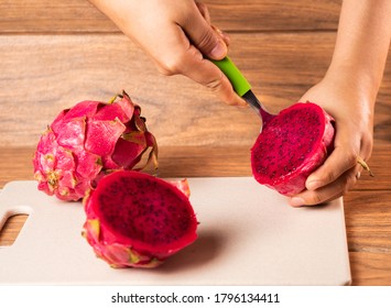 A High Angle Shot Of A Person Peeling A Red Dragon Fruit With A Spoon