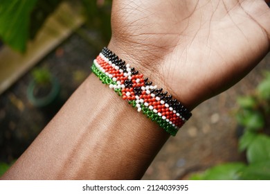 A high angle shot of a person wearing a handmade bracelet of the Kenyan flag
