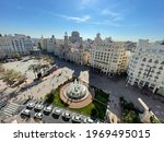High angle shot of Plaza del Ayuntamiento with fountain and walking people. Architectural scene of Valencia, Spain