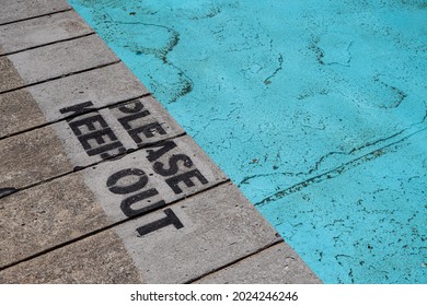 A high angle shot of a "Please Keep Out" sign on the wooden pier over the water