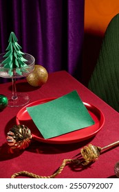 High angle shot at a red dining table with many luxury christmas decorations, a green empty paper displayed on red dish for adding text. Purple curtain standing out on orange background