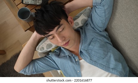 High Angle Shot With Restless Asian Japanese Male Taking A Nap On The Sofa In The Living Room At Home