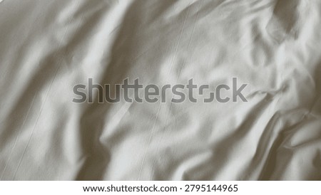 High angle shot of rumpled white fabric with subtle stripes and soft natural lighting.