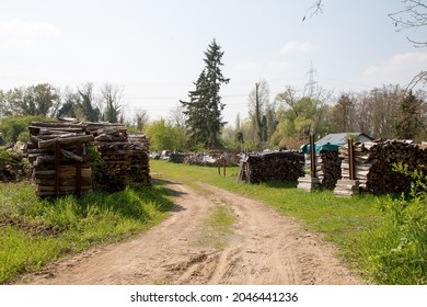 A High Angle Shot Of A Rural Landscape With Dirt Road And Piled Wood On The Lawn