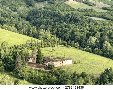 High angle shot of a rustic stone farmhouse surrounded by lush green hills and forests