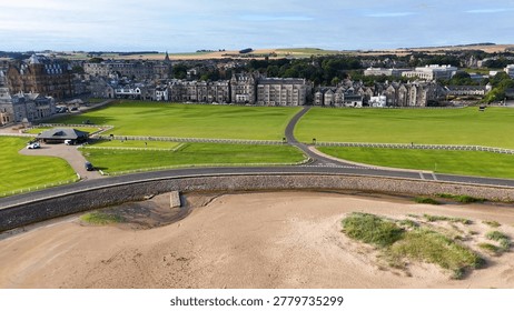 High angle shot of a sandy beach bordering a green golf course and town.
