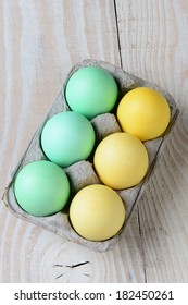 High Angle Shot Of A Six Pack Of Easter Eggs On A Rustic Kitchen Table. Vertical Format.