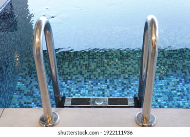 A High Angle Shot Of A Stainless Steel Ladder On A Swimming Pool