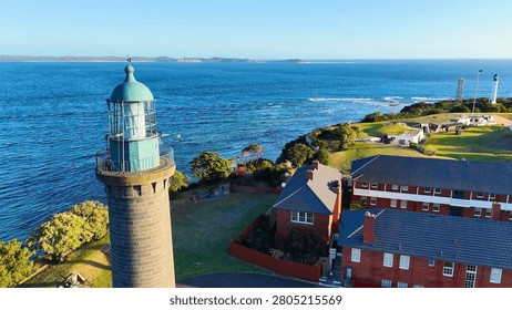 High angle shot of a stone lighthouse overlooking the ocean and coastal buildings in Australia.