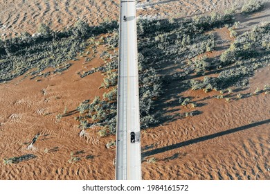 A High Angle Shot Of A Straight Road Leading Through A Desert With Dry Plants