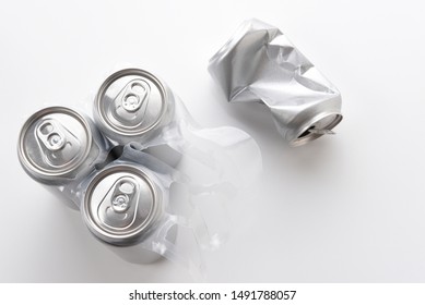 High Angle Shot Of A Three Aluminum Cans In Plastic 6 Pack Carrier And One Crushed Empty Can. Cans Have No Label. 