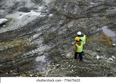 High Angle Shot Of Two Industrial Workers Wearing Reflective Jackets Walking In Dirt On Mining Worksite Outdoors Using Digital Tablet, Copy Space