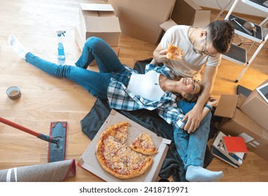 High angle shot of young smiling couple enjoying pizza while lying on the floor at their new apartment. - Powered by Shutterstock