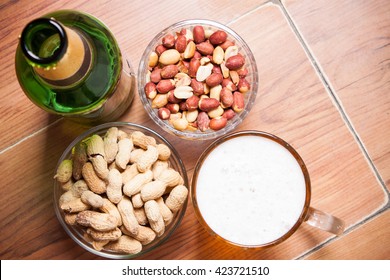 High Angle Still Life View of Glass of Cold Ale, Bottle of Beer, Bowl of Peanuts and Bottle  on Rustic Wooden Table with Copy Space.
