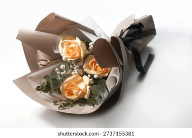 High angle studio shot of an elegant bouquet featuring three champagne roses nestled with white baby's breath and green eucalyptus foliage. The arrangement is professionally wrapped in layered muted brown and white kraft paper, finished with a stylish black ribbon bow. Set against a clean white background, this minimalist and romantic floral composition is ideal for Valentine's Day, Mother's Day, anniversaries, or luxury gift concepts.