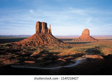 High Angle And Sunset View Of Road And Red Rock Cliffs Against Desert And Land Horizon At Monument Valley, Arizona, United States
