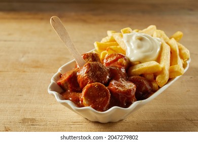 High angle of tasty fast food dish of fried pork sausage chunks with hot chips and curry ketchup on brown background - Powered by Shutterstock