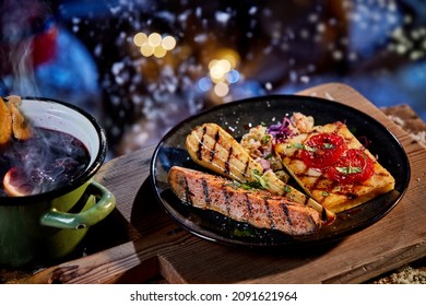 High Angle Of Tasty Grilled Parsnip Near Sweet Potato And Haloumi With Tomatoes Served On Wooden Tray On Backyard At Winter Night