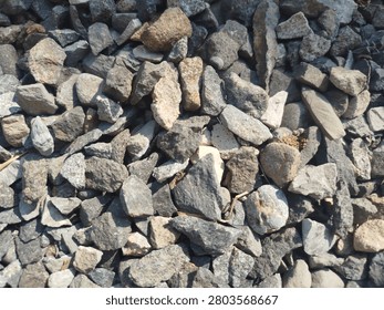 High angle texture of scattered grey and brown mineral pebbles, gravel for construction and gardening