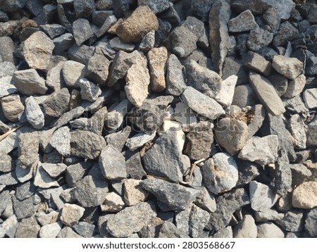 High angle texture of scattered grey and brown mineral pebbles, gravel for construction and gardening