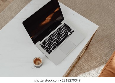 High angle top view of an open laptop placed on a wooden table alongside a cup of coffee.