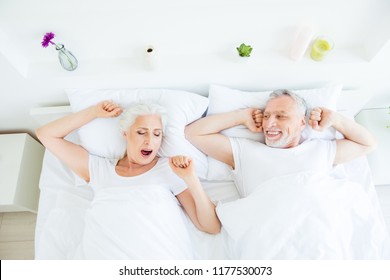 High angle top view photo of two aged grey hair people wake-up on morning weekend in white sheets and blanket in the lovely bright house - Powered by Shutterstock