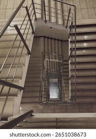High angle top view of a rectangular spiral staircase receding down, abstract architectural geometry, dizzying perspective of endless stairs in a modern building.