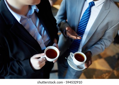 High Angle Of Two Business People Interacting During Coffee Break: Unrecognizable Businessman Talking To Colleague Gesturing And Holding Cups With Tea