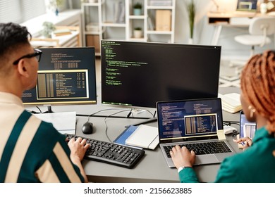 Gran angular de dos desarrolladores de TI que utilizan equipos mientras revisan el código en la oficina