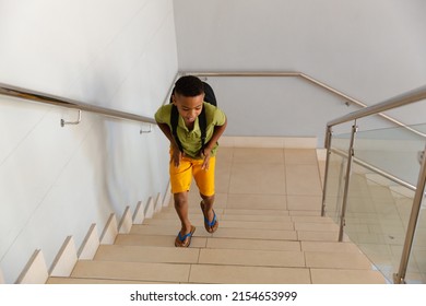 High angle view of african american elementary schoolboy with backpack climbing steps in school. unaltered, education, childhood and school concept. - Powered by Shutterstock