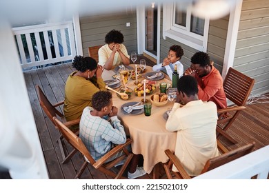 High Angle View At African American Family Saying Grace At Dinner Table With Eyes Closed