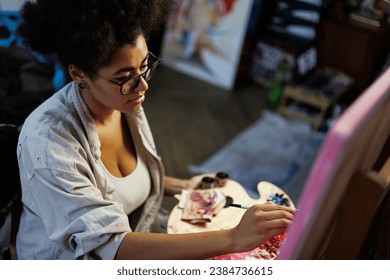 High angle view of african american artist painting on canvas in blurred art studio	 - Powered by Shutterstock