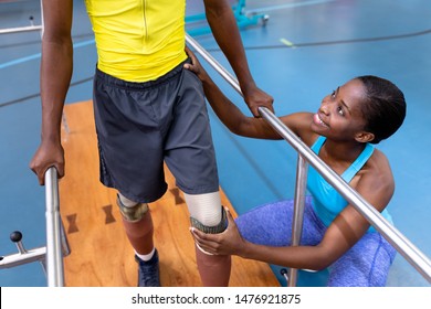 High angle view of African-american physiotherapist assisting disabled African-american man walk with parallel bars in sports center. Sports Rehab Centre with physiotherapists and patients working - Powered by Shutterstock