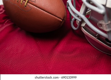 High Angle View Of American Football And Helmet On Red Jersey