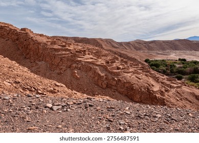 High angle view of the ancient stone fortifications and ruins of Pukara de Quitor archaeological site overlooking the green river valley in the Atacama Desert, Chile