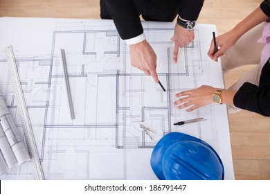 High Angle View Of Architects Working On Blueprint At Desk In Office