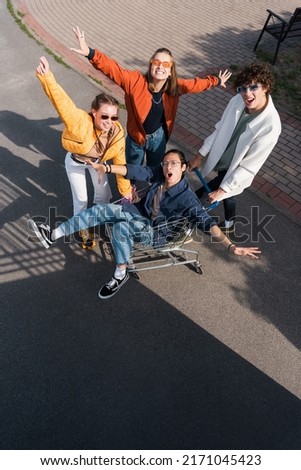 high angle view of asian man screaming in shopping trolley near excited friends