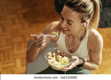 High Angle View Of Athletic Woman Enjoying In Healthy Salad After Sports Training At Home. 