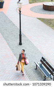 High Angle View Of Attractive Woman Walking With Shopping Bags On Street