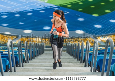 high angle view of attractive young woman jogging upstairs at sports stadium