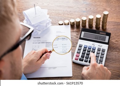 High Angle View Of A Auditor Hand Calculating Invoice Using Calculator On Desk. Tax Scrutiny And Fraud Investigation Concept - Shutterstock ID 561913570