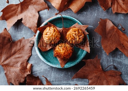 high angle view of an autumn leaf in a plate holding various Catalan panellets with pine nuts and almonds, typical sweets for All Saints Day in Catalonia, Spain
