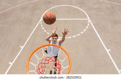 High Angle View from Backboard of Young Athletic Man Taking Lay Up Shot on Net on Outdoor Basketball Court - Powered by Shutterstock